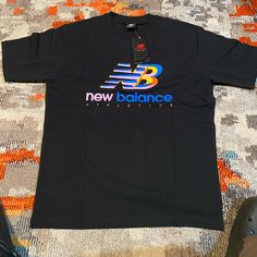 This Is A Brand New T Shirt With Tags Black With Pink,Red,Blue And Yellow In The Logo Casual New Balance Crew Neck T-shirt, New Balance Crew Neck Cotton T-shirt, New Balance Casual Short Sleeve Tops, Casual New Balance Short Sleeve Top, Baseball Graphic Tees, New Balance White, Blue Shorts Men, Black Fitness, New Balance Black