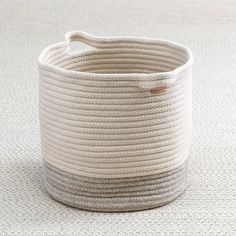 a large white rope basket sitting on top of a carpet