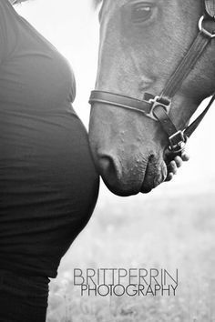 a black and white photo of a pregnant woman kissing a horse