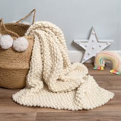 a white blanket sitting on top of a wooden floor next to a basket