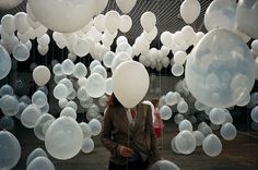 a woman standing in front of white balloons