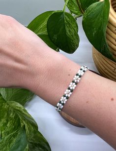 a person's arm with a bracelet on it next to a potted plant