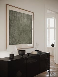 a black and white room with a large painting hanging on the wall next to a dresser