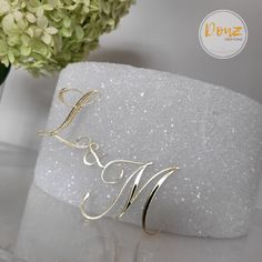 a gold ring with the word love on it sitting next to a white vase filled with flowers