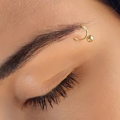 a woman's eye with a gold nose pin in the shape of a crescent