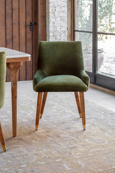 two green chairs sitting next to each other in front of a table with a glass door