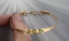 THIS BRACELET IS WATER PROOF AND TARNISH RESISTANT  ELEGANT PERIDOT    GEMSTONE  BANGLE BRACELET IN  14KT ROLLED GOLD  HAS 3 4MM PERIDOT GEMSTONES  IN IT  HANDCRAFTED IN 14KT ROLLED GOLD  IN A UNIQUELY DESIGNED SETTING UNIQUE HANDCRAFTED PIECE THAT WILL GET YOU NOTICED! LIGHTWEIGHT AND EASY TO WEAR SIZE ----- SIZE 6 TO 8 BRACELET IS 1/4 OF AN INCH WIDE ON THE SIDES BRACELETE IS  1/2   INCH WIDE IN FRONT iTS COMFORTABLE HEAVY DUTY HOOK AND CATCH MAKES IT EASY TO TAKE ON AND OFF AN EYE CATCHING PIECE! WEAR IT CASUAL OR FORMAL 7 THINGS TO KNOW ABOUT 14KT ROLLED GOLD #1. 14 Kt Rolled gold wire is also called gold filled wire------This gold wire was used extensively in the 1800's and early 1900s. It is not used very much today its too expensive.  It is durable that is it is very, very strong an Sculpted Jewelry, Make Up Gold, Gemstone Bangle Bracelets, Wire Wrapped Bangles, Peridot Bracelet, Gemstone Bangle, Bracelet Gemstone, Peridot Gemstone, Bracelet Cuff