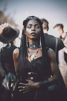 a woman with black makeup and braids standing in front of other people wearing hats