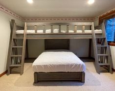 a bunk bed sitting in the middle of a room with two ladders above it