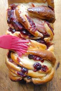 a hot dog bun with bacon, cheese and jelly on it is being held by a red spatula