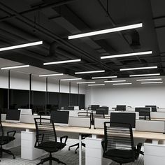 an empty office with desks and chairs in the middle, along with hanging lights