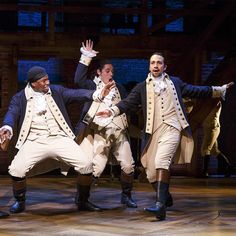 five men dressed in period clothing are dancing on stage