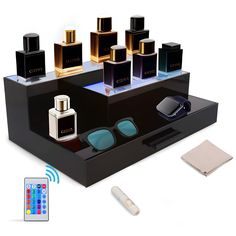 an assortment of perfumes on display in a black box with remote control and accessories