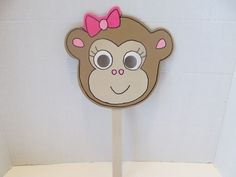 a cardboard monkey with a pink bow on its head is standing in front of a white wall