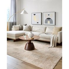 a living room with white couches and art on the wall above it, along with a coffee table