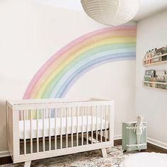 a white crib with a rainbow painted on the wall