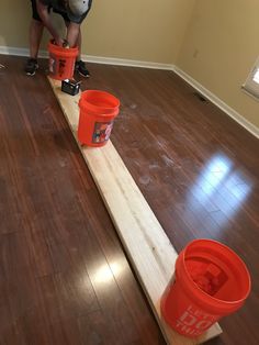 two buckets are sitting on top of a long piece of wood that is being worked on