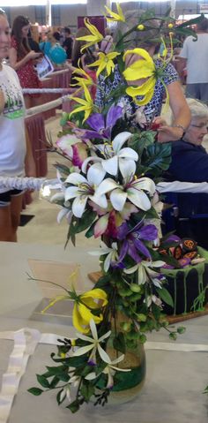 there is a cake with flowers on it and people in the background looking at it