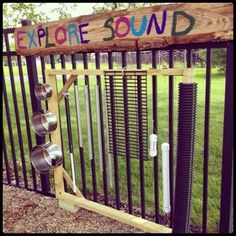 there is a sign that says explore sound on the side of a fence with pots and pans attached to it