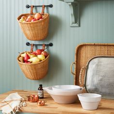 two baskets with apples, pears and other fruit in them hanging on the wall