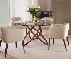 a glass table with chairs around it and a vase on the table next to it