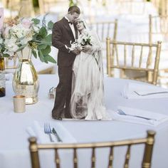 a bride and groom standing next to each other on a table with flowers in vases