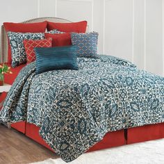 a bed with red and blue comforters in a room next to a white wall