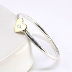 a heart shaped ring with a diamond in the middle on top of a white surface