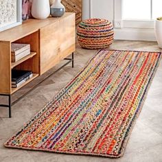 a living room with a large rug on the floor next to a wooden cabinet and window