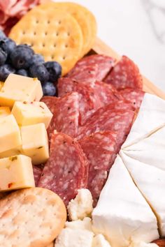 an assortment of cheeses, meats and crackers on a platter