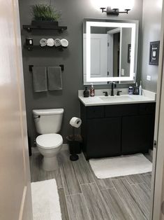 a bathroom with gray walls and white fixtures, including a sink, toilet, and mirror