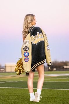 a woman standing on top of a field holding a cheerleader's pom pom