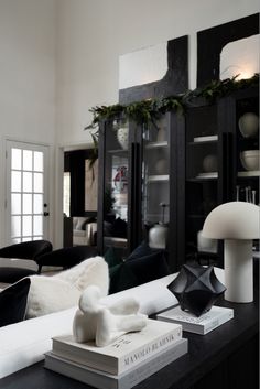 a living room with black and white furniture, books on the coffee table, and christmas decorations