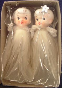 two plastic dolls are sitting in a box