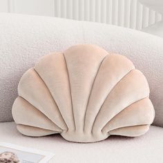 a shell shaped pillow sitting on top of a white couch next to a photo frame