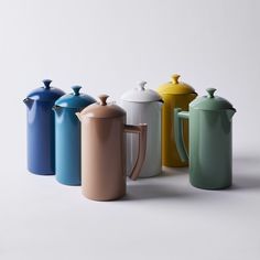 four different colored coffee pots and one teapot