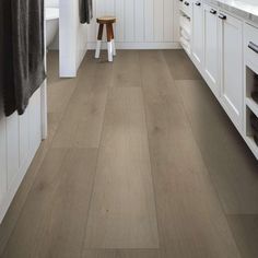 a bathroom with white cabinets and wood flooring on the walls, along with a wooden stool