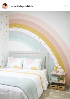 a white bed sitting under a rainbow painted wall