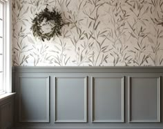 an empty room with wallpaper and a wreath on the wall, in front of a window