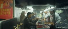 several people standing around a food cart with donuts on it's trays