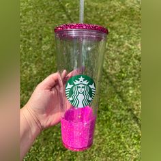 a person holding up a starbucks cup with pink glitter on the bottom and purple sprinkles around it