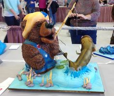 there is a cake that looks like a bear playing with a fish on the table