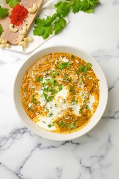 a white bowl filled with soup and garnished with cilantro on top