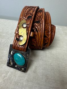 Very unusual vintage belt , or I should say it's an unusual buckle on a stylish tooled leather belt.  It has "BJ" engraved in a brass piece, and what looks to be a large turquoise stone set into the buckle. I believe the buckle is likely brass, but it looks silver in color.  It's one of a kind for sure.  In great shape, no flaws to note.  Sorry I don't know much more about it really.  ✏️✏️✏️DETAILS✏️✏️✏️ Brand: hand made Size on tag: - Fits like: small men's 31  Color:  2 tone brown with silver, Western Antique Belt Buckles For Festival, Southwestern Antique Belt Buckle For Rodeo, Southwestern Antique Belt Buckles For Ranch, Rustic Hand Tooled Belt Buckles For Western Events, Rustic Antique Buckle Belt For Rodeo, Rustic Belts With Antique Buckle For Western-themed Events, Rustic Concho Belt Buckles For Rodeo, Rustic Antique Belt Buckle For Rodeo, Rustic Belt With Antique Buckle For Western-themed Events