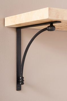 a wooden shelf mounted to the side of a wall with black metal brackets on it