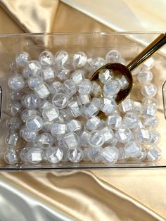 a glass container filled with white beads and a pair of tongs on top of it