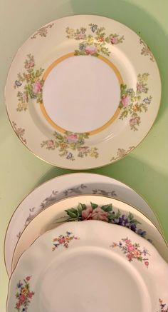 three plates are stacked on top of each other, one is white and the other has pink flowers