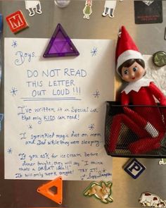 an elf is sitting on top of a refrigerator with magnets and paper attached to it