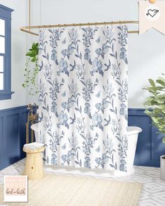 a blue and white bathroom with a shower curtain, rug and potted plant in the corner