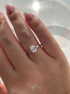 a woman's hand with a diamond ring on top of her left hand,